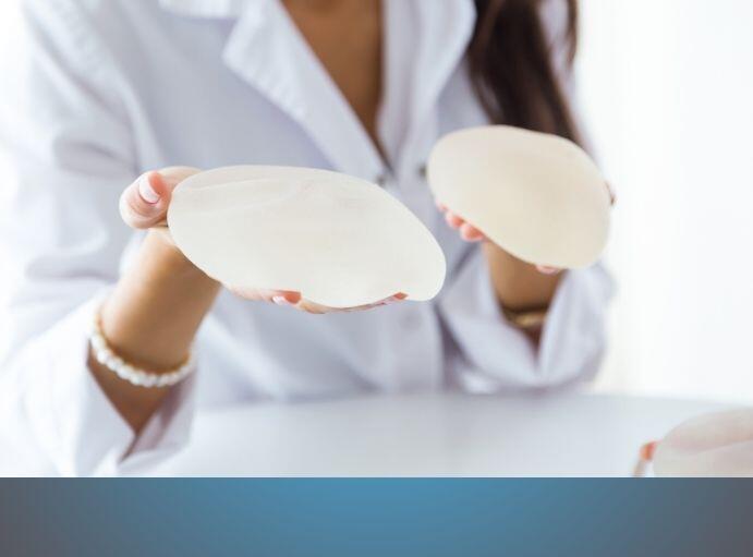 Pacjentka kobieta pokazuje implanty a chirurg tlumaczy cena powiekszania piersi w Poznaniu